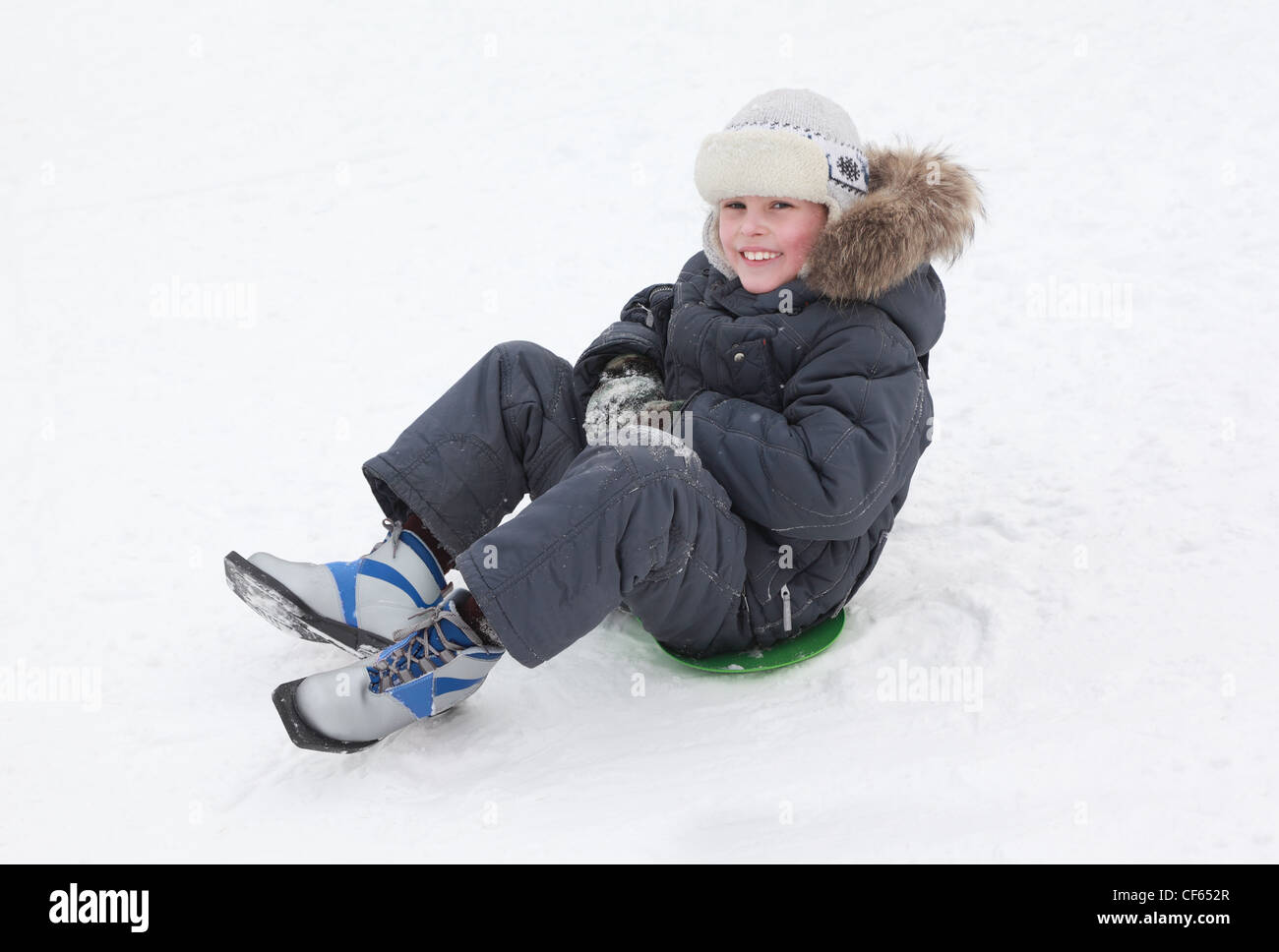 Junge lächelnde junge Schlittschuhe auf grüne Eis-Boot auf reinen weißen Schnee Stockfoto