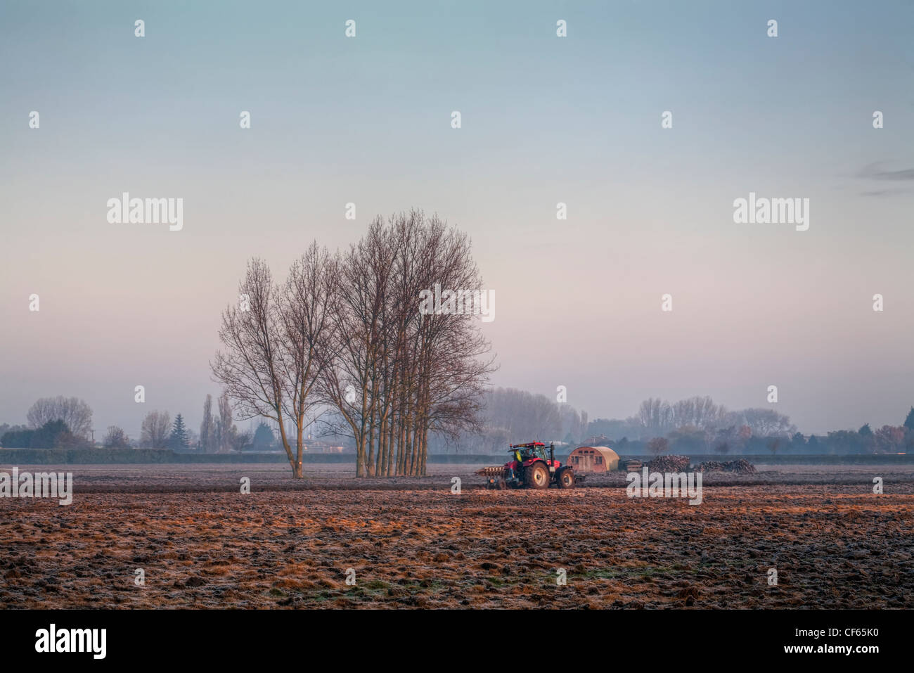 Ein Traktor Pflügen Frost bedeckt Feld in den frühen Morgenstunden. Stockfoto