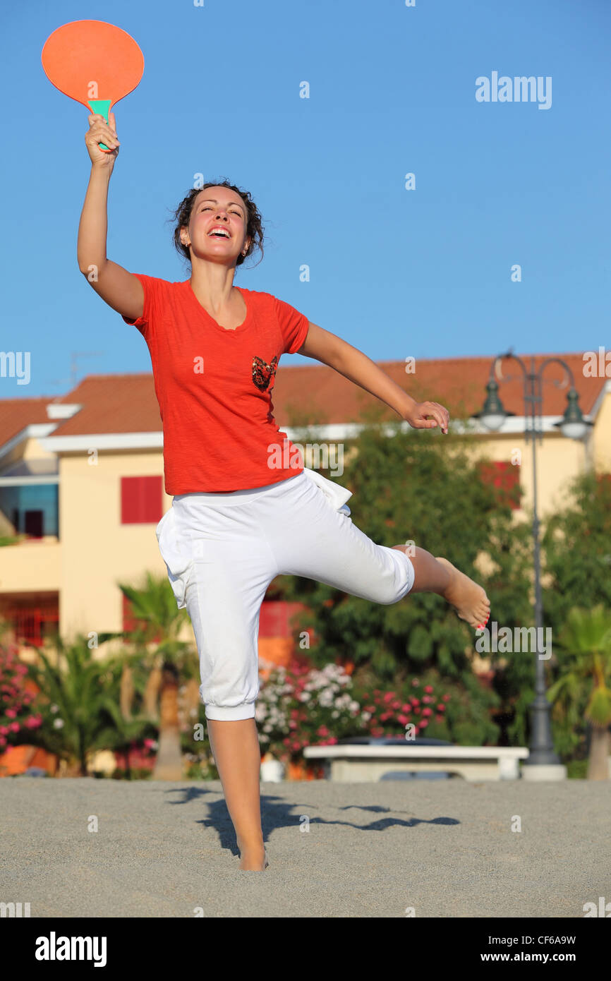 Frau springt mit Tennisschläger am Strand tagsüber Sonne Stockfoto