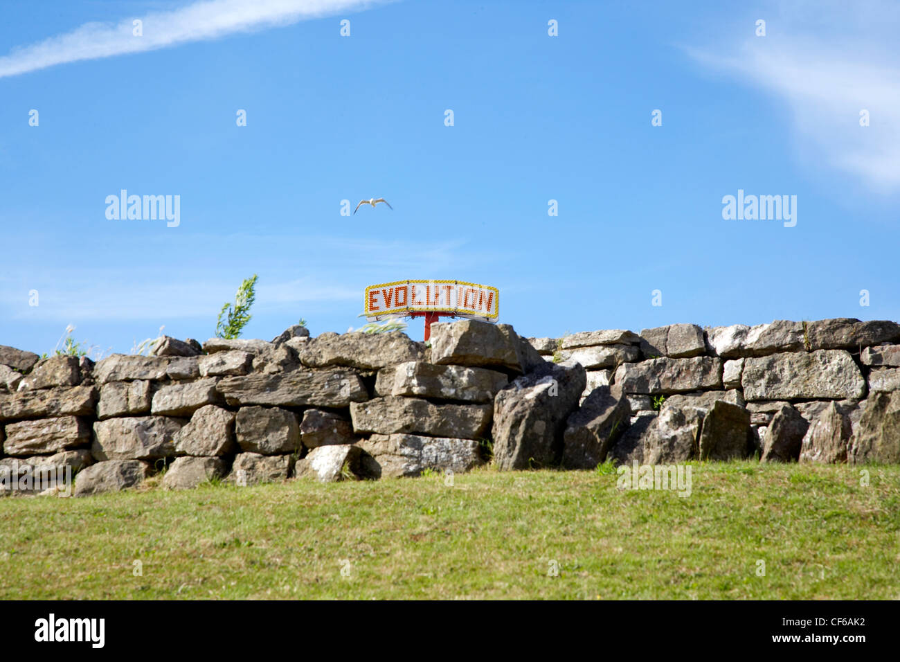 Die Oberseite einer Kirmes-Fahrt ist sichtbar hinter einer alten Steinmauer auf Barry Island in Glamorgan. Stockfoto