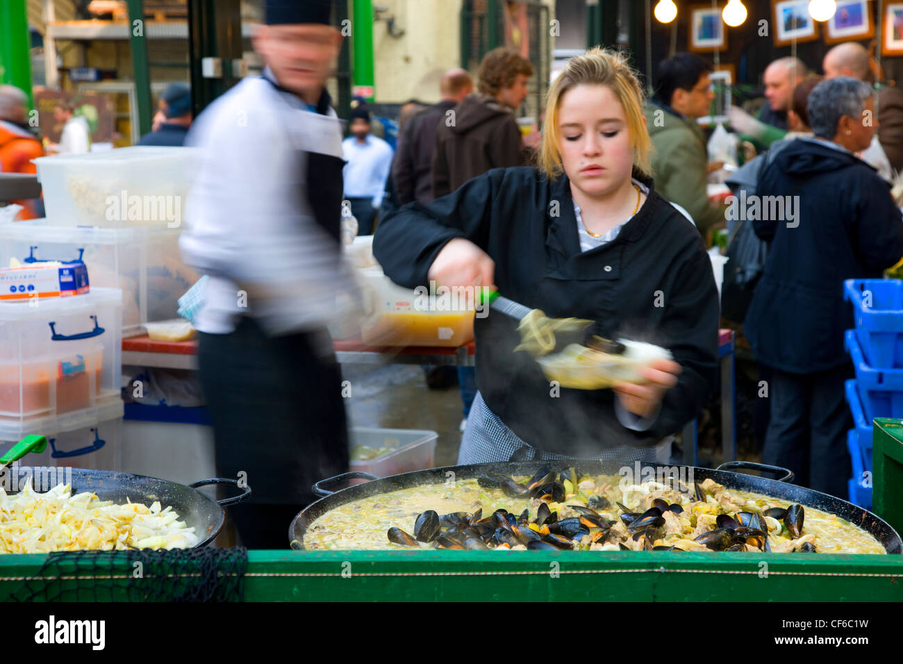 Ein junges Mädchen servieren Paella im Borough Market in London. Stockfoto