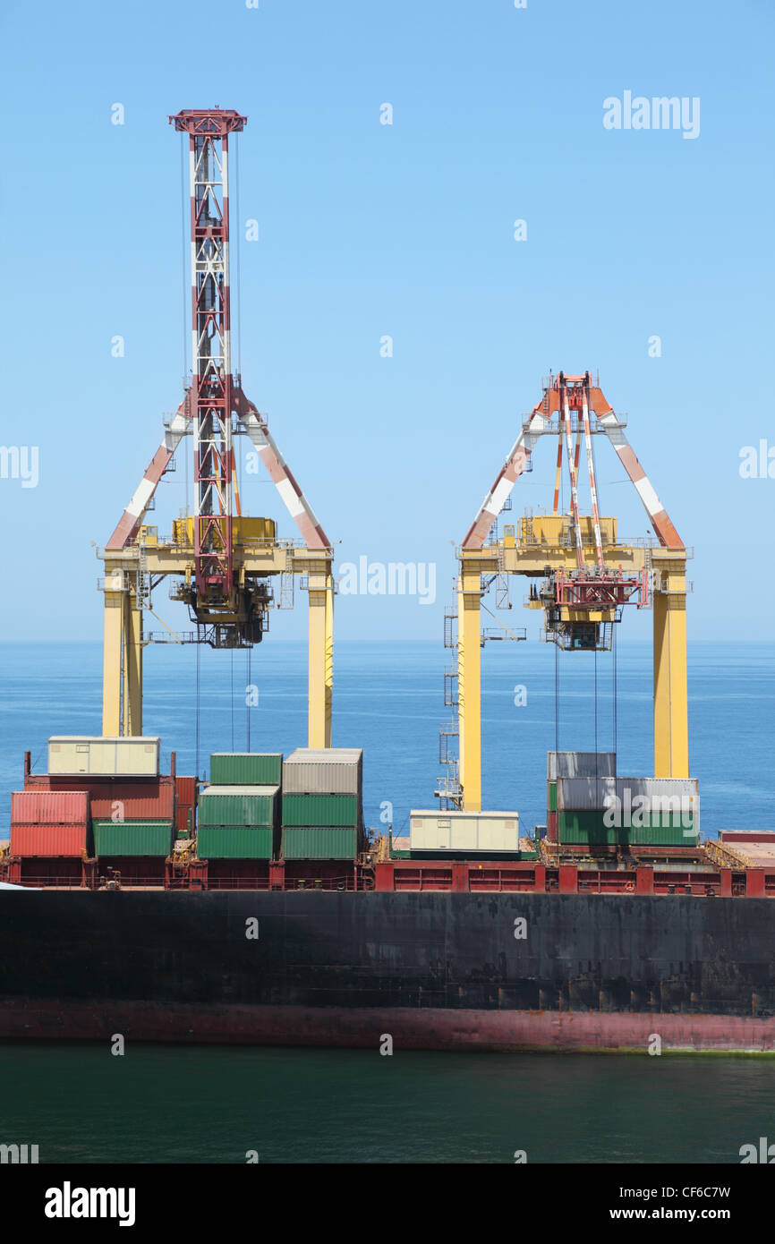 großes Handelsschiff mit vielen großen Ladungen auf einer Tafel im Hafen. Stockfoto