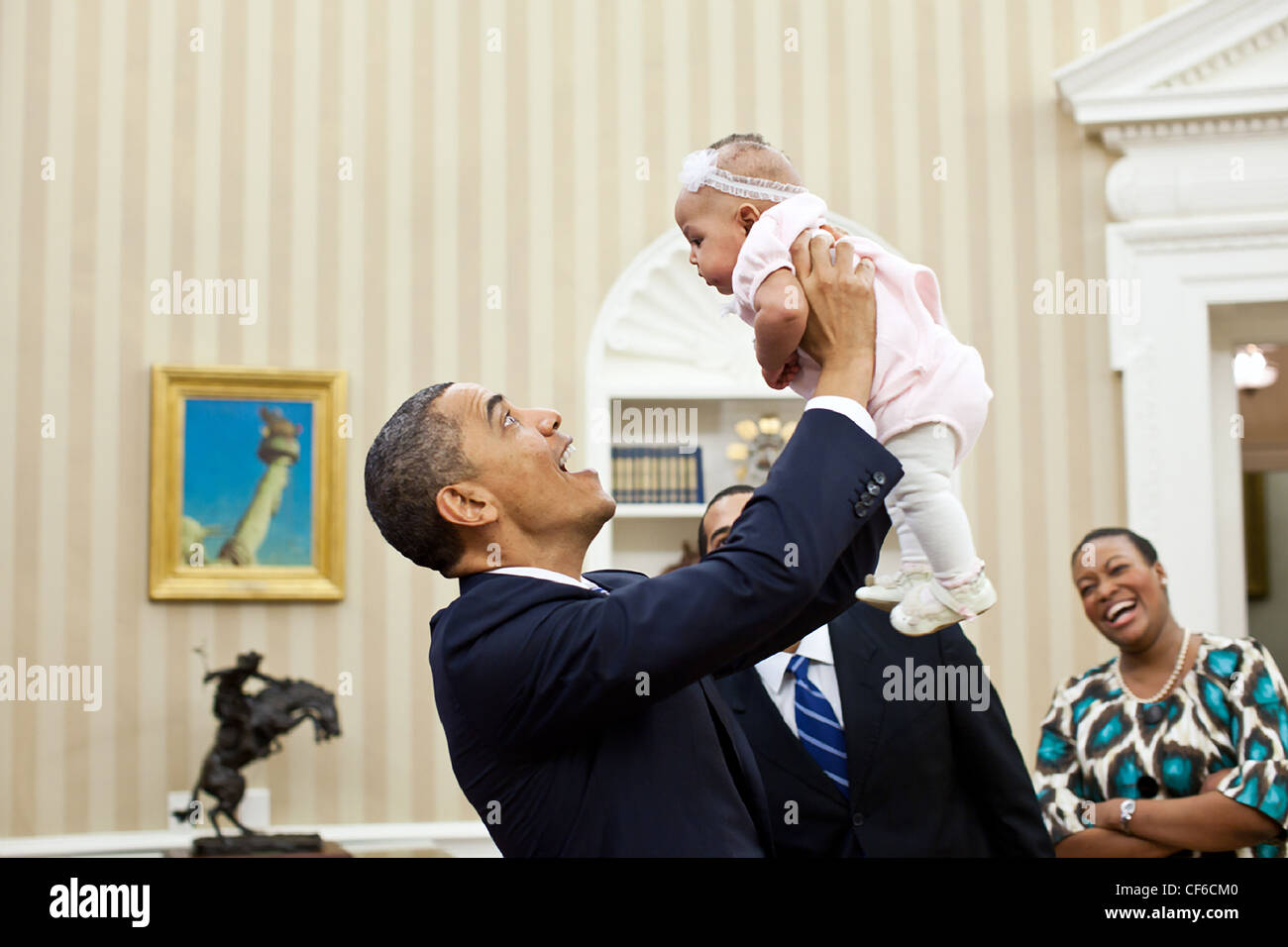 Präsident Barack Obama hält vier Monate alten Alia Jawando als ihr Vater William Jawando, Associate Vizedirektor des öffentlichen Engagements und ihrer Mutter Michele blicken auf im Oval Office 9. März 2011 in Washington, DC. Stockfoto