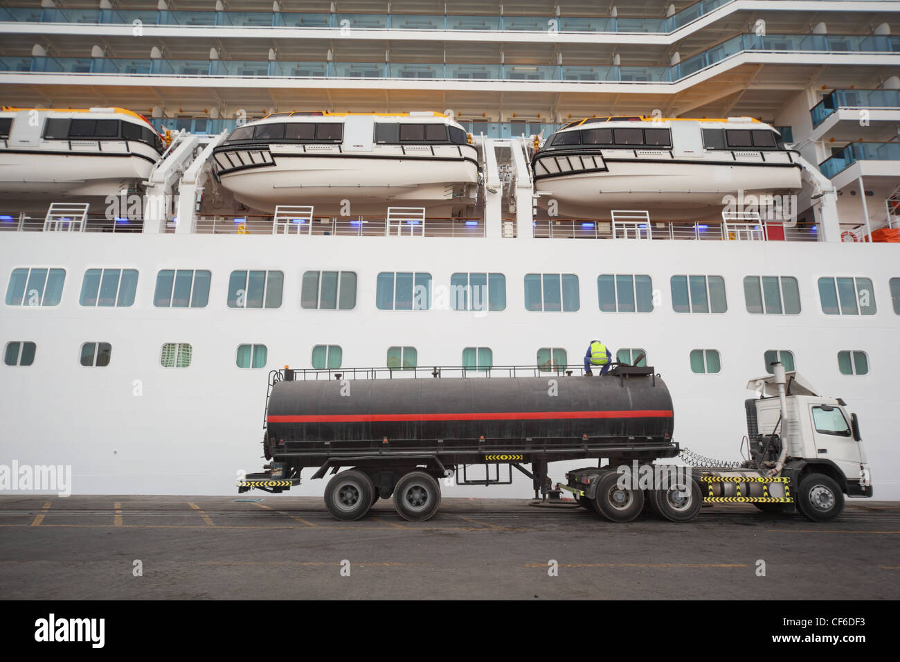 Gastank LKW im Qaboos Hafen zu bleiben. Kreuzfahrtschiff hinter LKW. Arbeiter auf LKW. Stockfoto