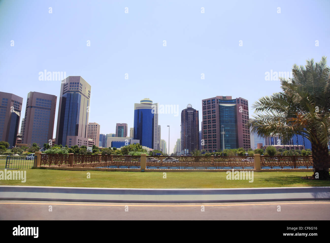 Grünen Rasen vor Abu Dhabi Hochhäuser. Der Blick aus einem fahrenden Auto. Stockfoto