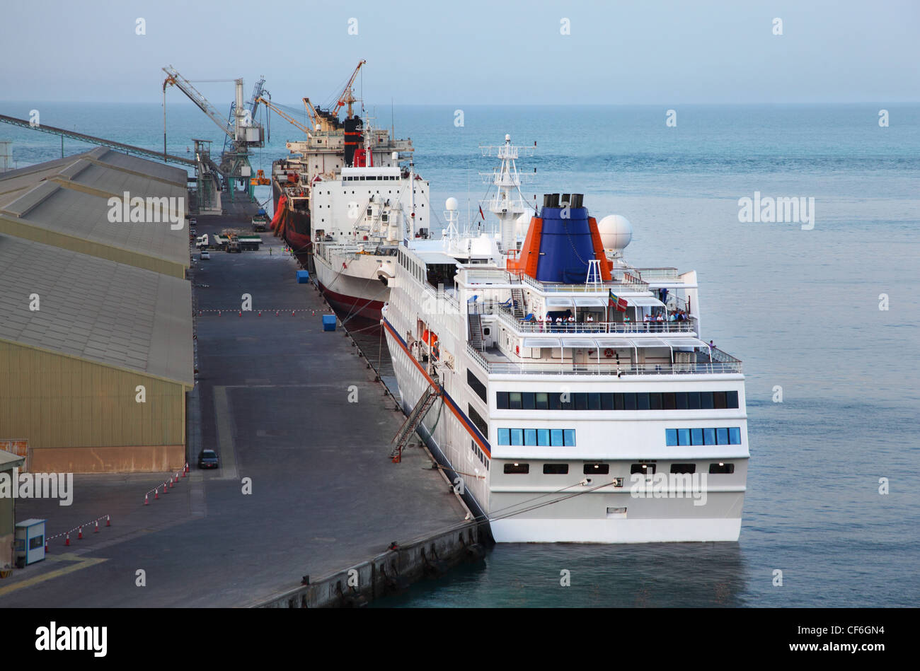 Große Kreuzfahrt-Liner, zwei Frachtschiffe und Kran in einem Hafen in Abu Dhabi Stockfoto
