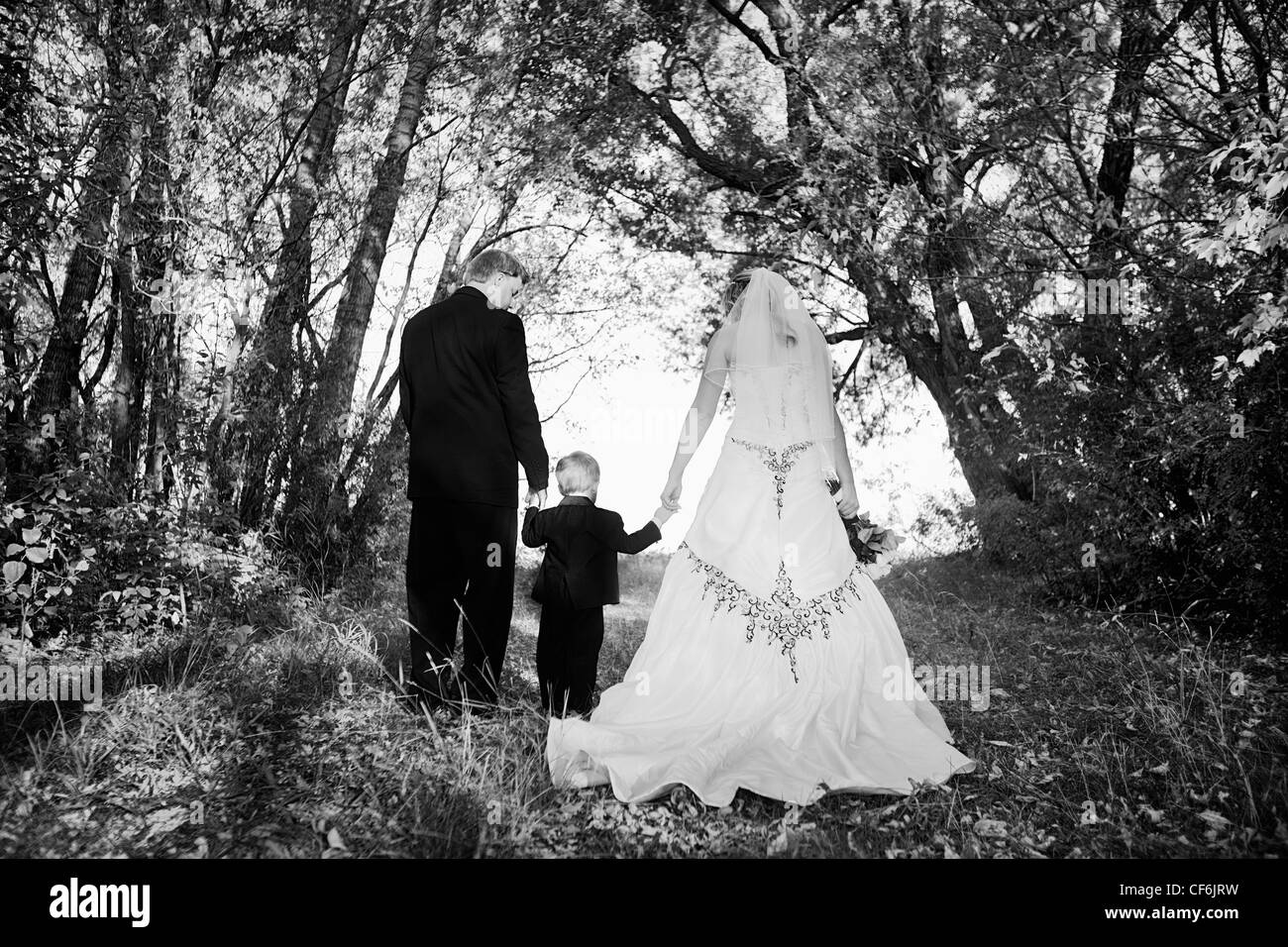 Eine Braut und Bräutigam zu Fuß und ein kleiner Junge Hand dazwischen halten; Edmonton Alberta Kanada Stockfoto