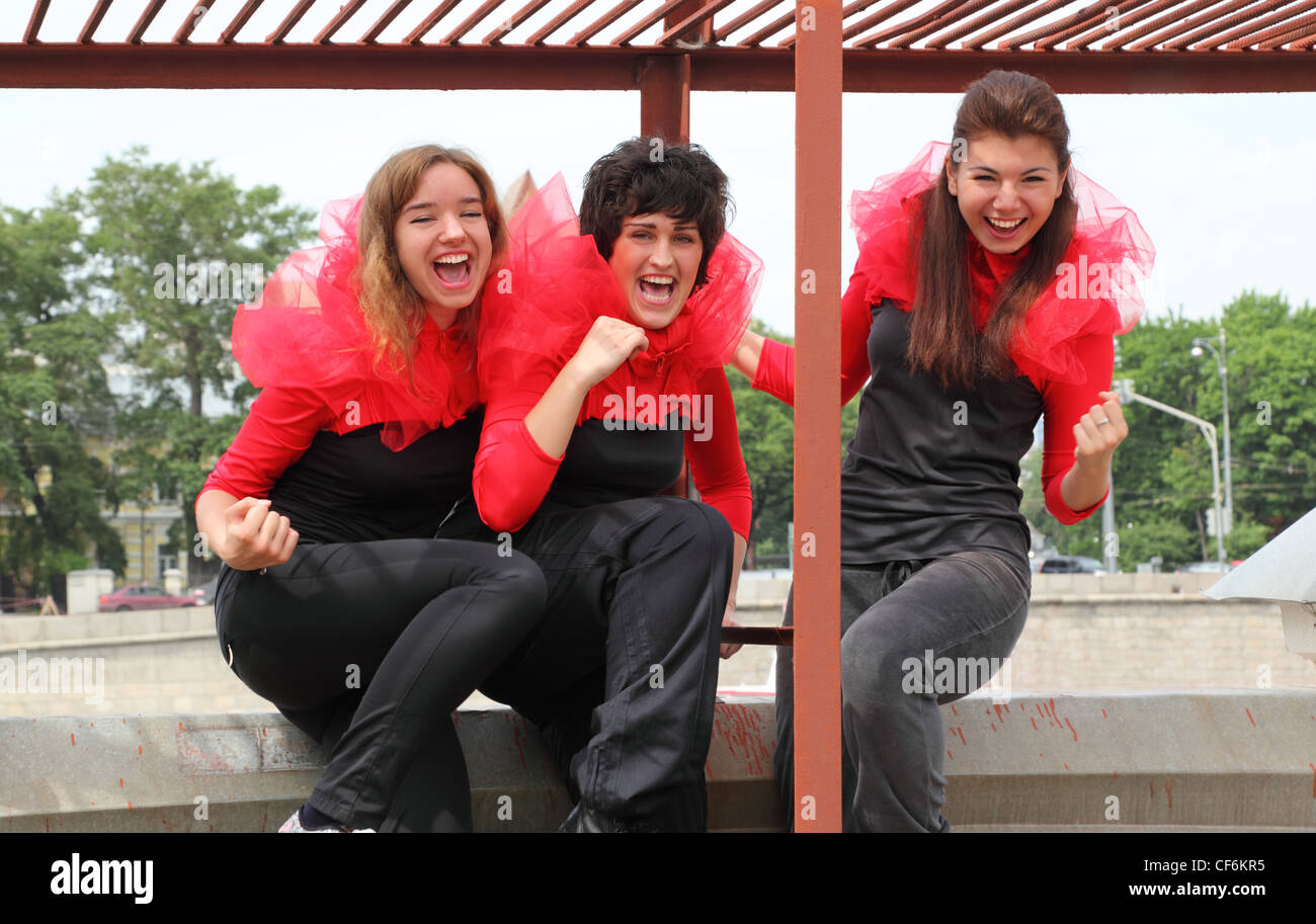 Drei Mädchen in der gleichen rot-schwarze Kleidung steht auf Dach auf Hintergrund der Stadt Stockfoto