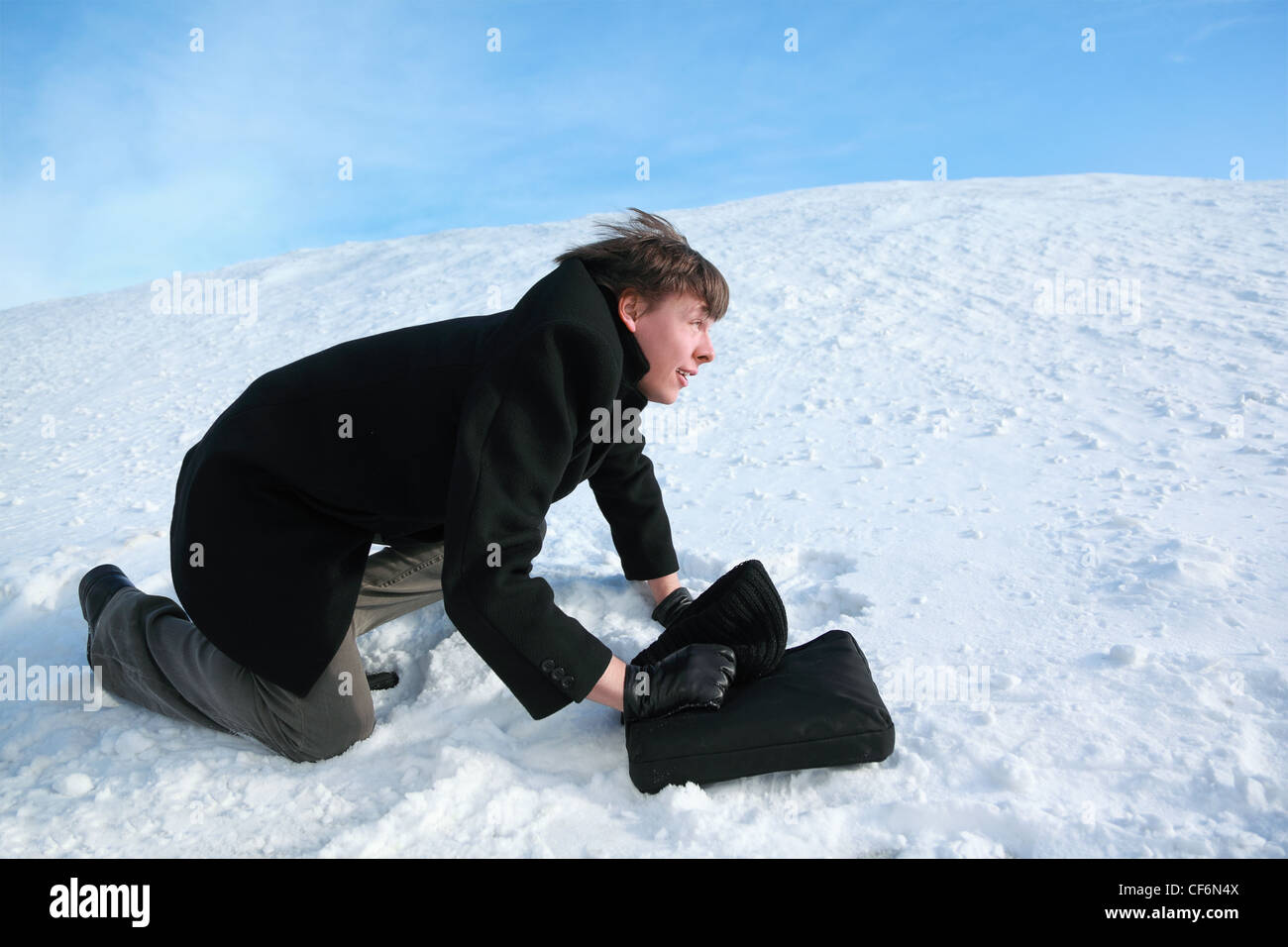 Junger Mann kriecht auf allen Vieren auf Schnee mit Slip-case Stockfoto