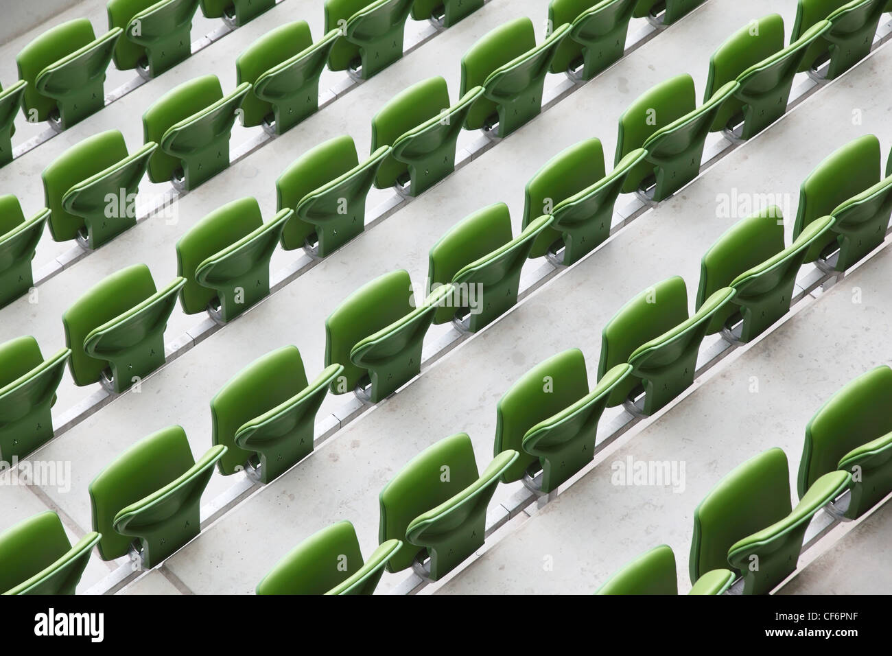 Viele Zeilen grün, Kunststoff, Klappsitze in einem großen leeren Stadion. Stockfoto