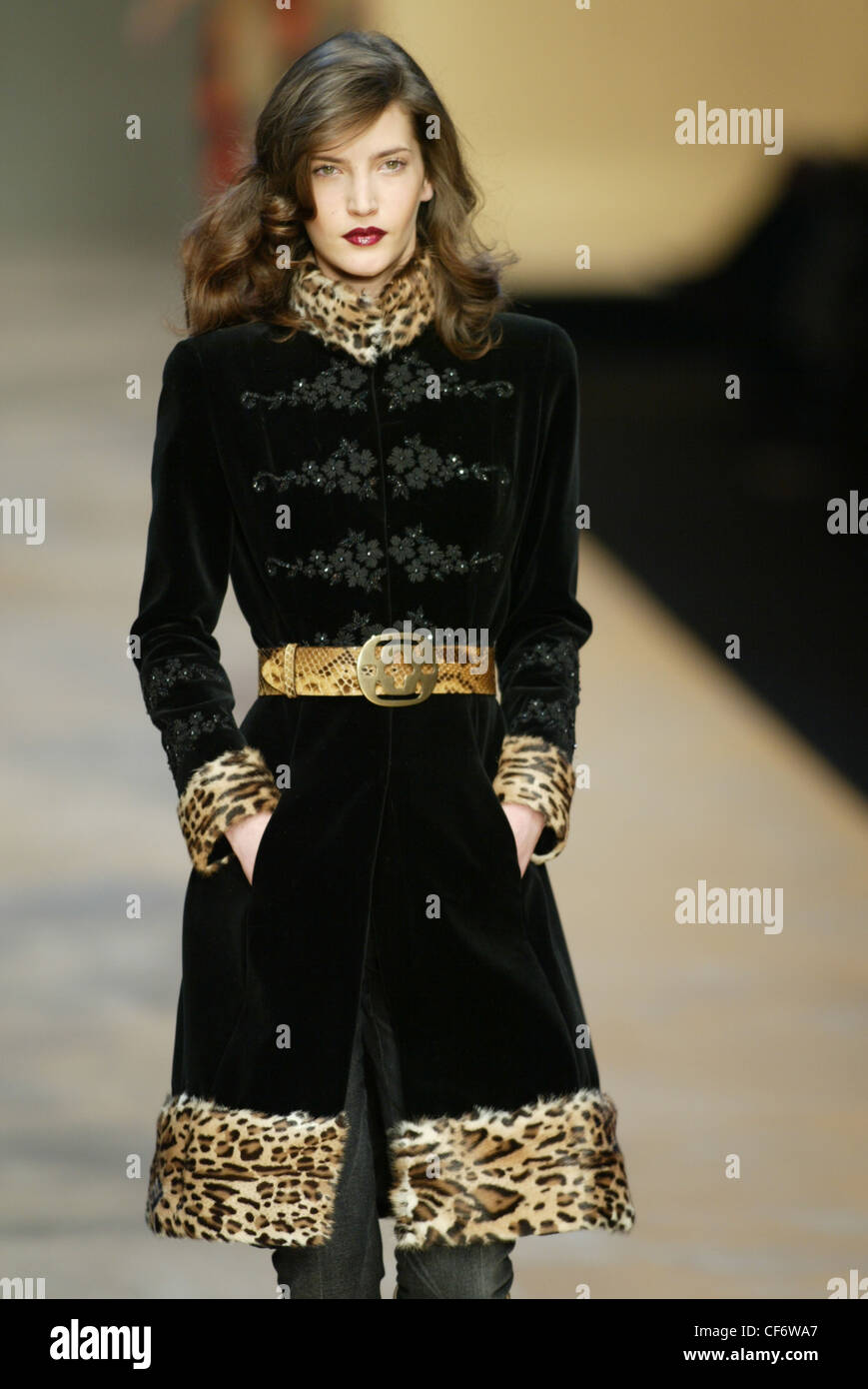 Blumarine-Mailand-Herbst-Winter-Modell lange gewellte brünette Haare tragen Knie Länge schwarzen Mantel schwarz floral Befestigung Details an Stockfoto