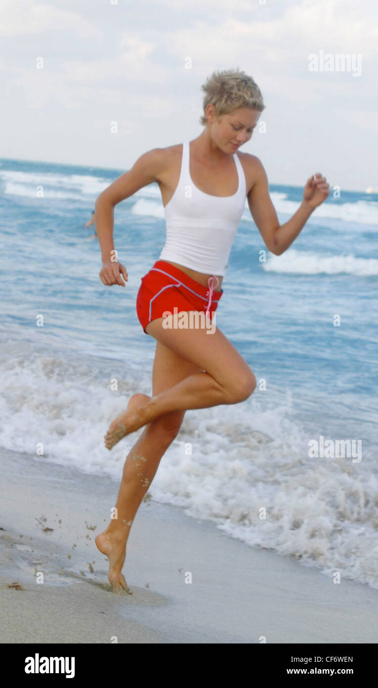 Weibliche Blonde Kurze Haare Tragen Weisse Weste Top Und Roten Hotpants Blau Trim Und Rosa Schleife Laufen Am Strand Am Rand Des Wassers Stockfotografie Alamy