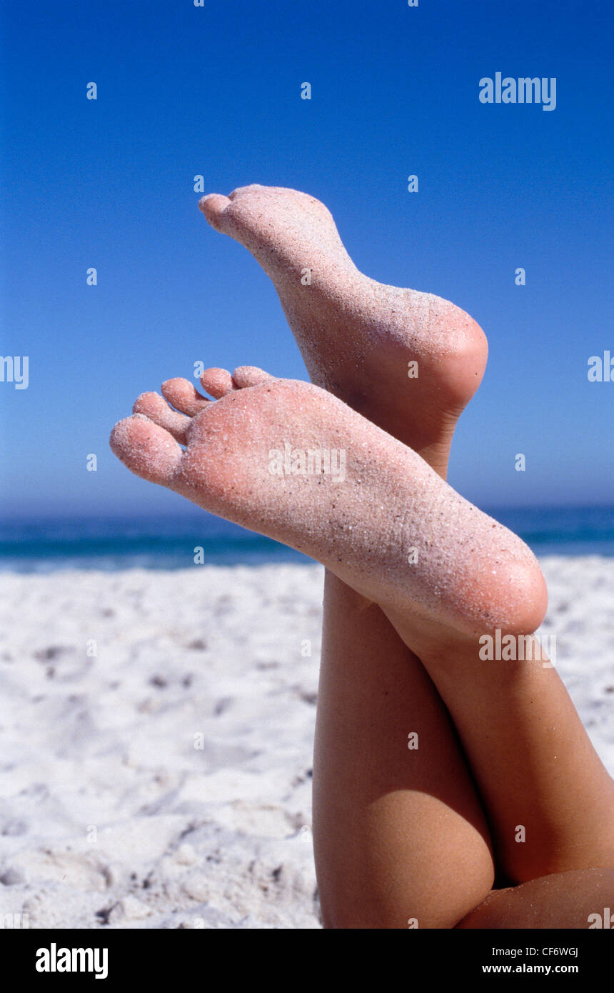 Zugeschnittenen Unterschenkel, aufgewachsen in Luft gekreuzt an Knöcheln, auf Unterseite beider Füße Sand Meer im Hintergrund Stockfoto