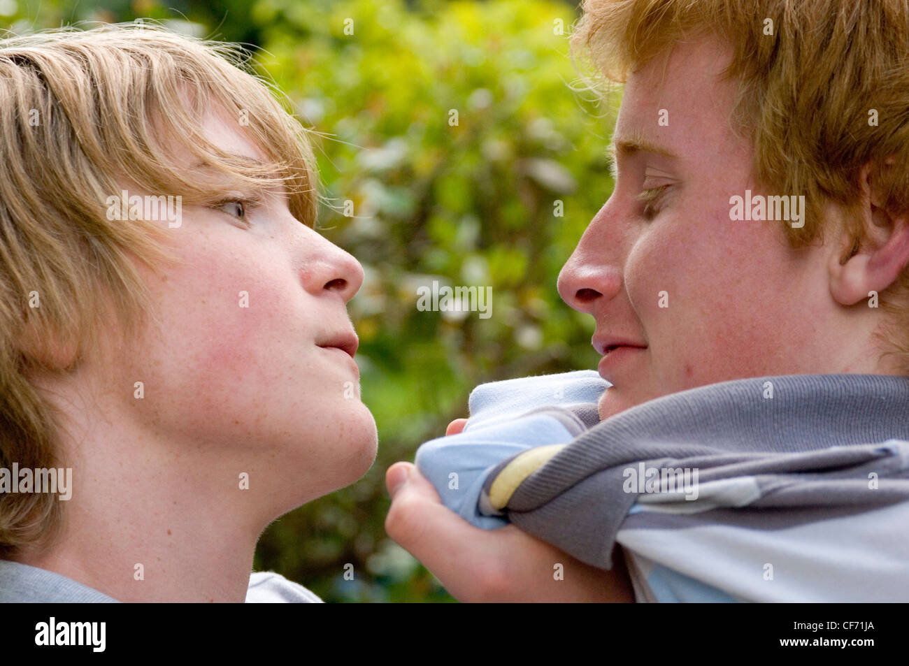 Zwei männliche Jugendliche spielen kämpfen im Garten Stockfoto