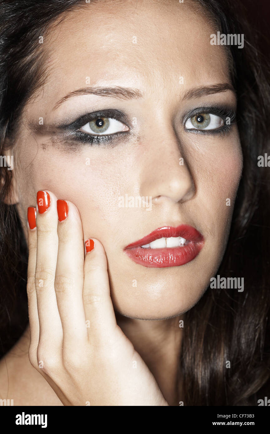 Weibchen mit Make-up verschmiert Auge und Hand auf Wange Stockfoto