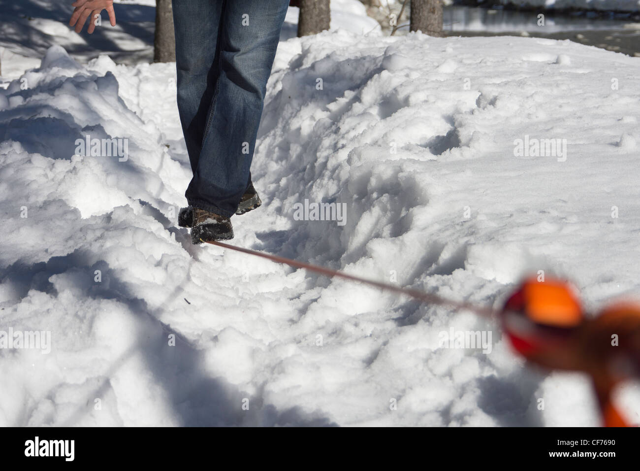 Mann zu Fuß auf einer Slackline über Schnee. Stockfoto