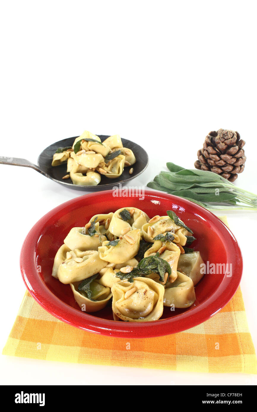 Rucola und Ricotta Tortellini mit Salbeibutter und Pinienkernen auf hellem Hintergrund Stockfoto