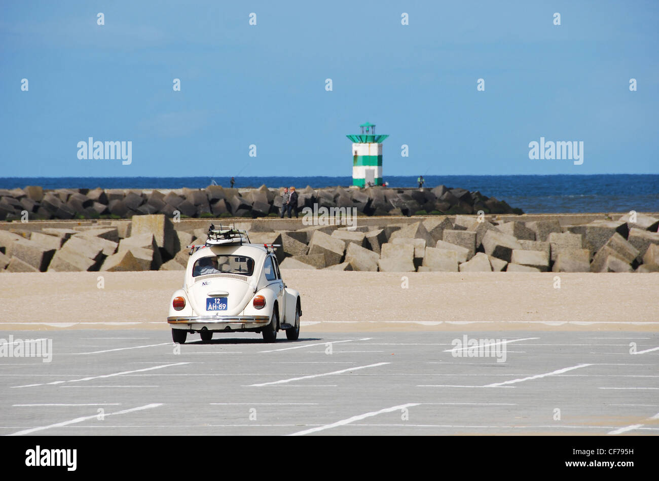 Klassische VW-Käfer mit Surfbrettern auf einem Parkplatz in der Nähe von Leuchtturm Stockfoto