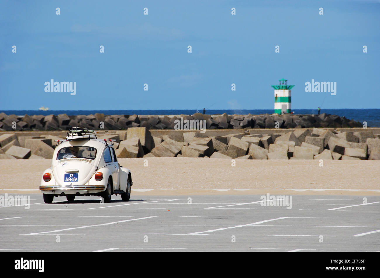 Klassische VW-Käfer mit Surfbrettern auf einem Parkplatz in der Nähe von Leuchtturm Stockfoto