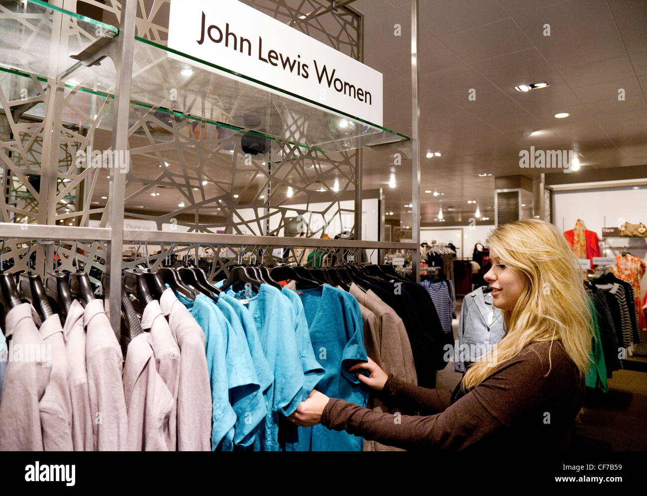 Ein junges Mädchen oder Junge Frau Kleidung einkaufen für Verkauf in John Lewis, Großbritannien Stockfoto