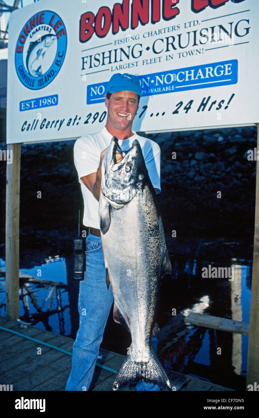 Ein glücklicher Fischer zeigt stolz die großen Königslachs, die er gefangen, während auf einem Sportfishing Boot aus Vancouver, British Columbia, Kanada. Stockfoto