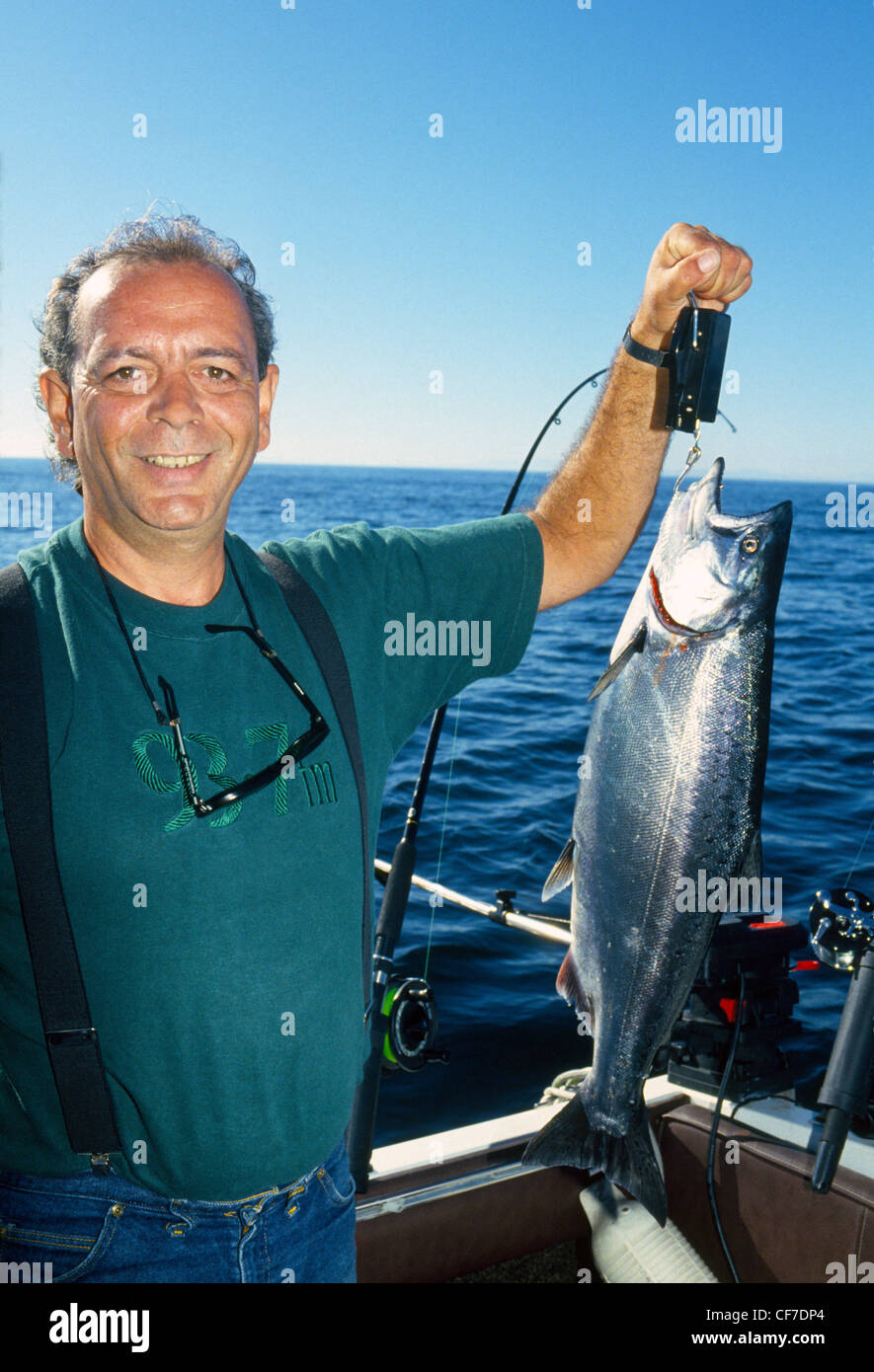 Ein Fischer zeigt stolz die silbrigen Königslachs, die er aus einem Sportfischen-Charter-Boot in der Nähe von Vancouver in British Columbia, Kanada gefangen. Stockfoto