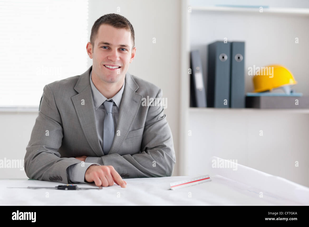 Lächelnde Architekt hinter dem Tisch sitzend Stockfoto