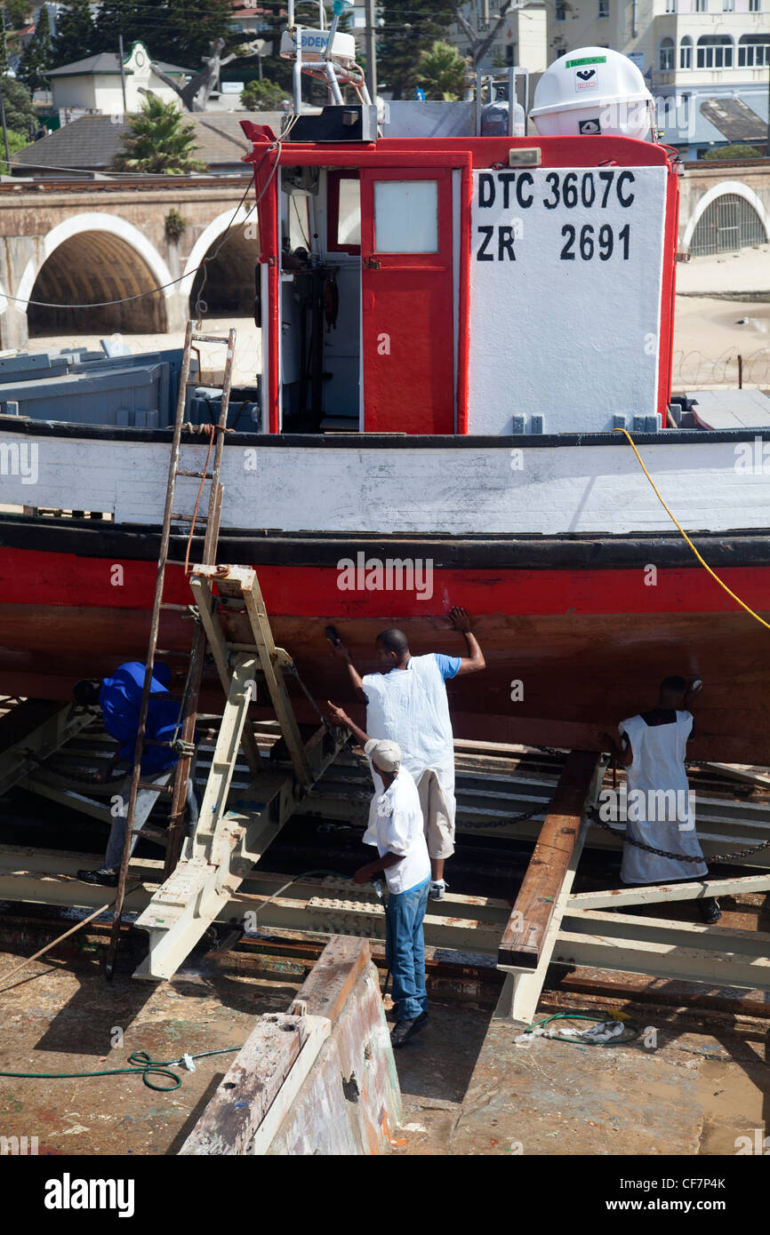 Arbeitnehmer, die Reinigung der Unterseite des Bootes in Kalk Bay - Kapstadt, Südafrika Stockfoto