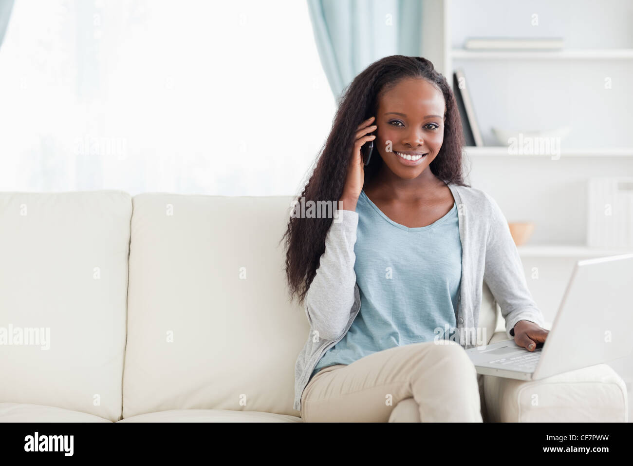 Frau mit Handy und Notebook auf dem sofa Stockfoto