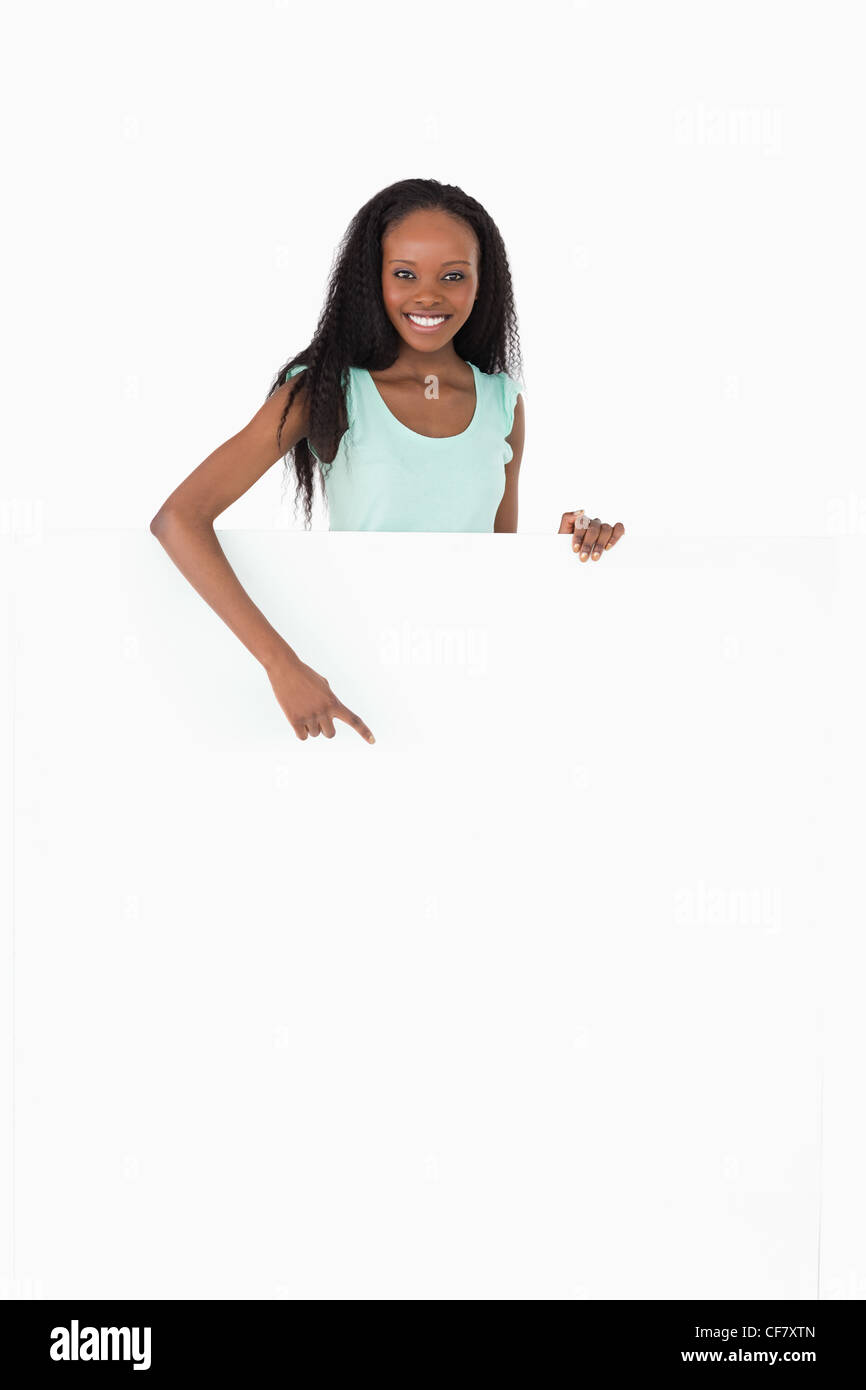 Frau zeigt auf Platzhalter unter ihr auf weißem Hintergrund Stockfoto