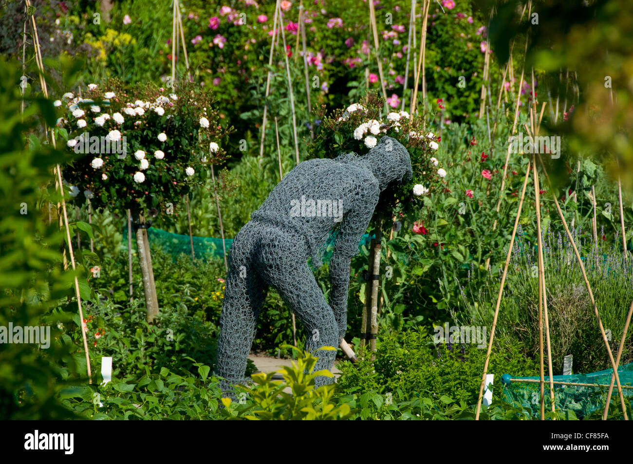Skulptur aus Draht in der Form eines Gärtners arbeiten in den Blumen