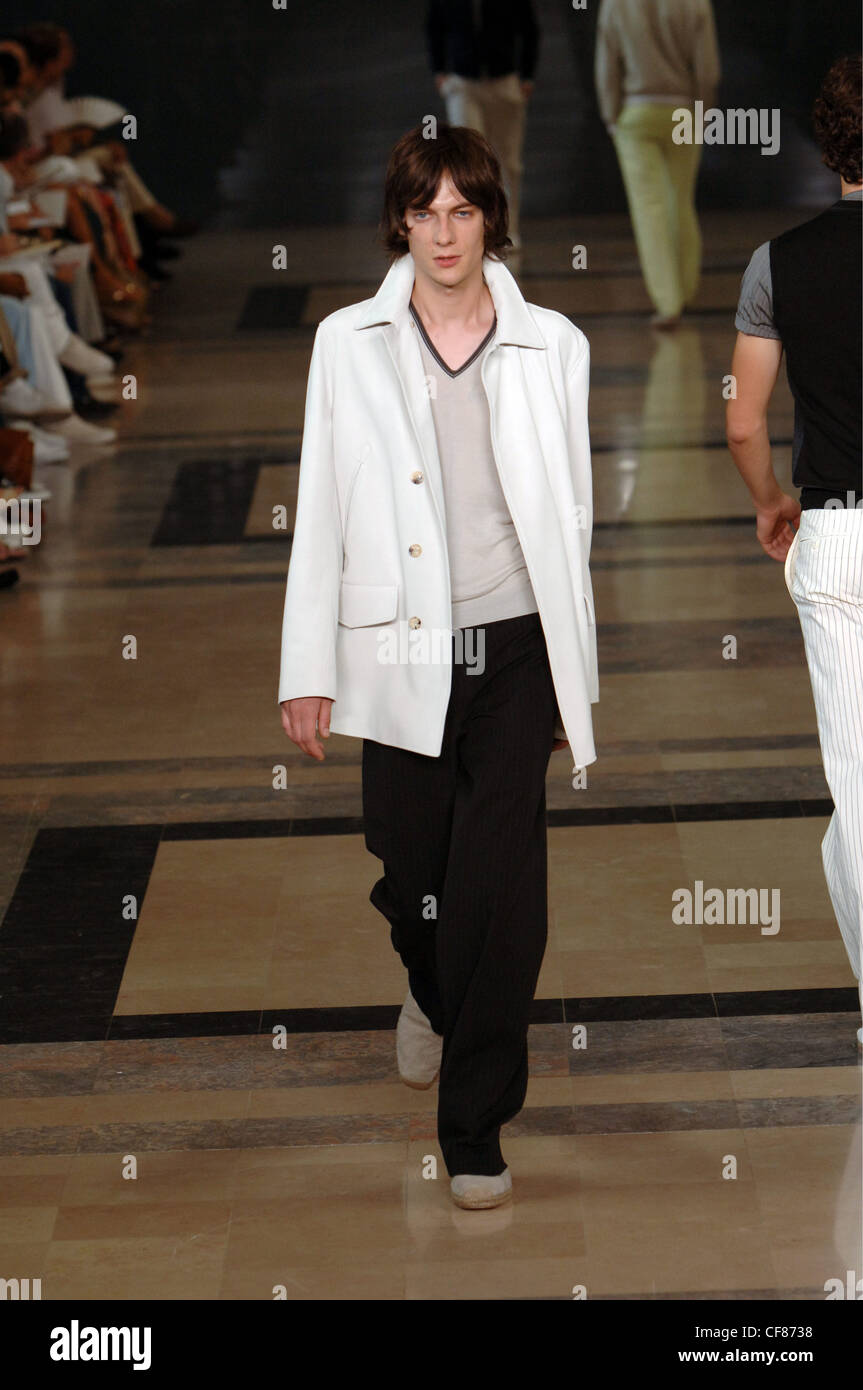 Hermes Paris bereit, tragen Menswear Frühjahr Sommer Brünette männlichen Modell eine weiße Peacoat schwarze Hosen aus weißem v-Ausschnitt Stockfoto