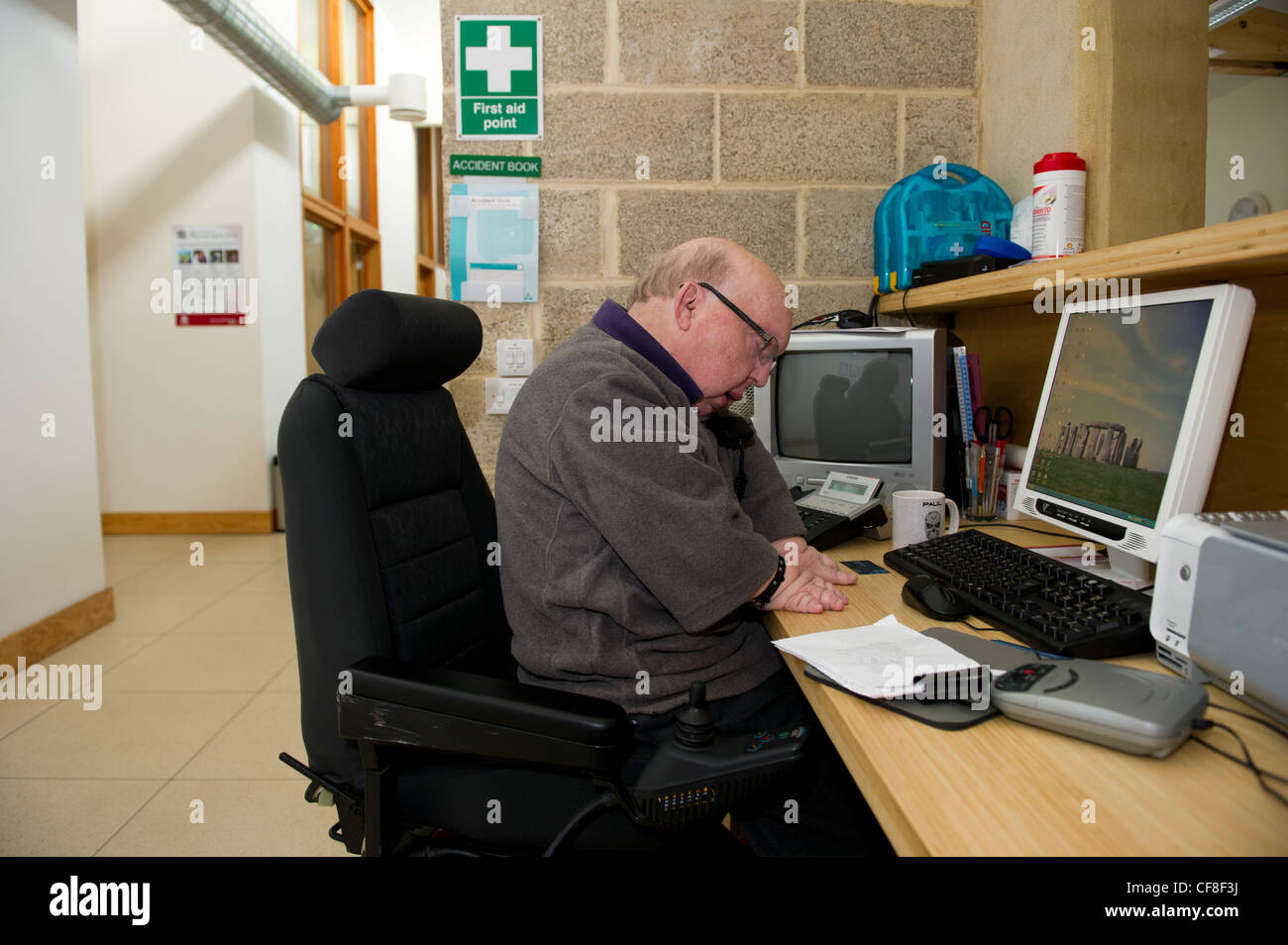 Ein behinderter Mann mit mehrere angeborene Fehlbildungen, die Arbeiten an der Telefon-Hotline am Sitz der Behinderung Essex. Stockfoto