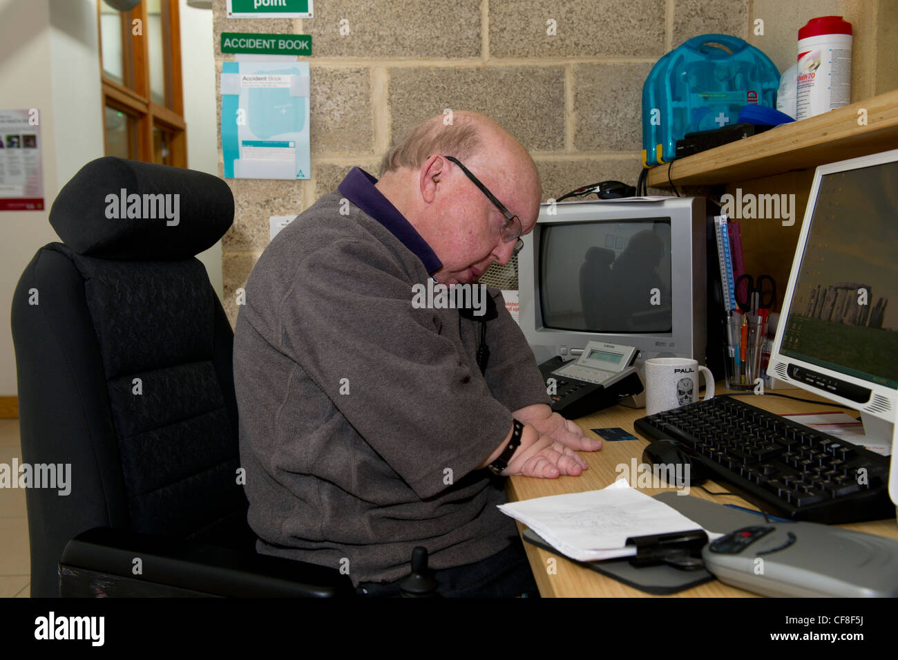 Ein behinderter Mann mit mehrere angeborene Fehlbildungen, die Arbeiten an der Telefon-Hotline am Sitz der Behinderung Essex. Stockfoto