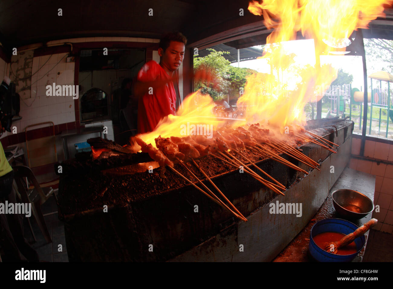 Der malaiische Mann bereitet ein lokales Gericht Satay. Stockfoto