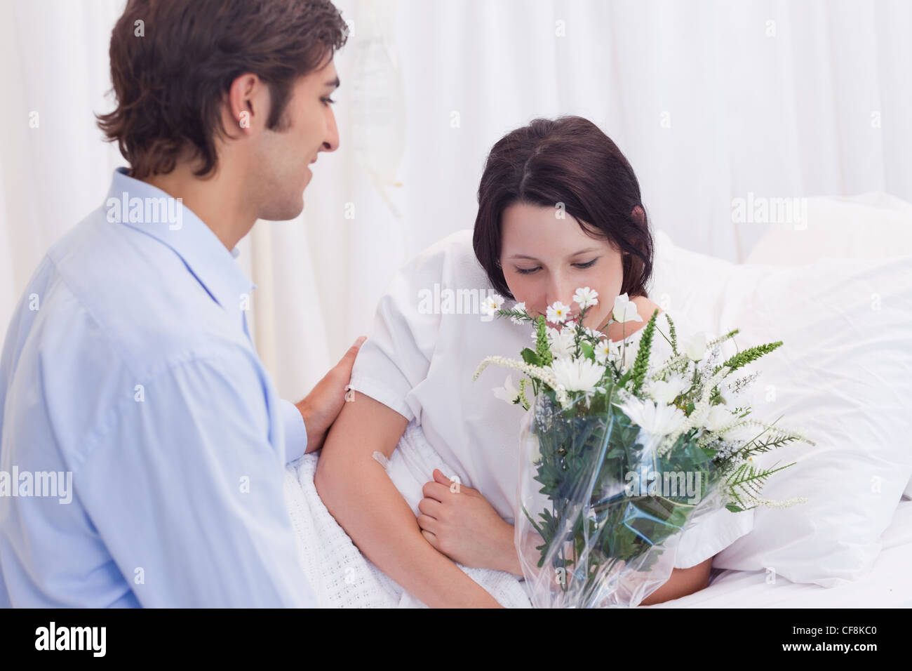 Nimmt Man Blumen Aus Dem Krankenhaus Mit Nach Hause Man brachte Blumen zu seiner Freundin im Krankenhaus Stockfotografie
