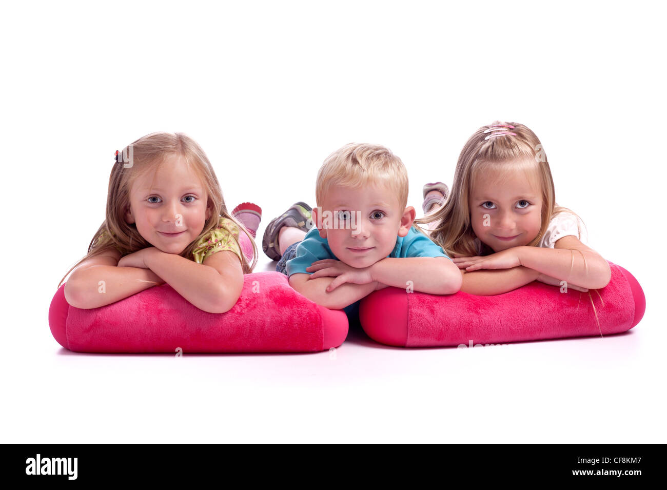 Littlle junge mit seinen 2 Schwestern. Auf rosa Kissen liegend. Isoliert auf weißem Hintergrund Stockfoto