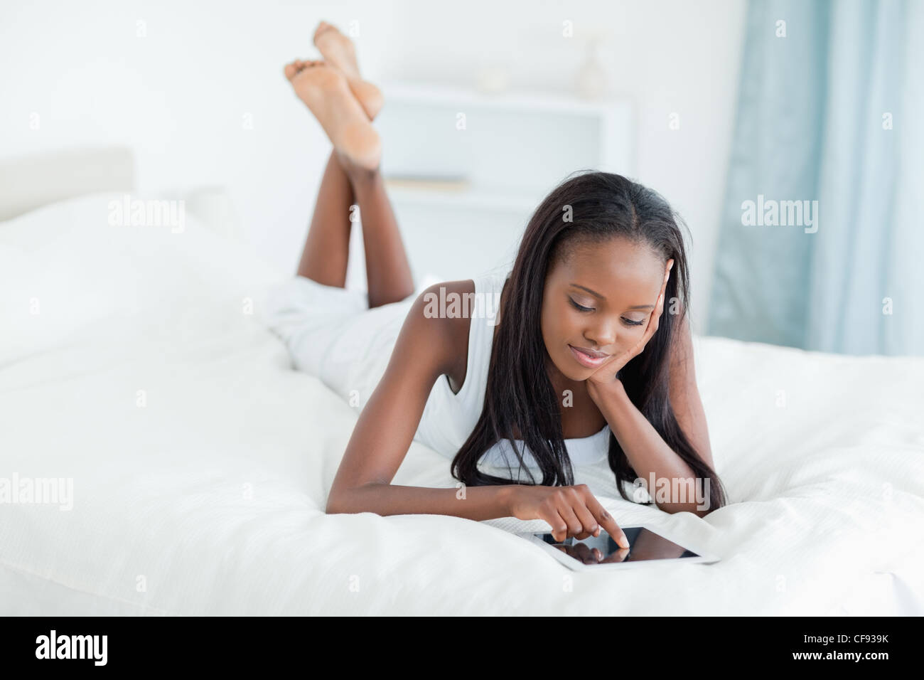 Frau mit einem Tabletcomputer auf ihrem Bett liegend Stockfoto