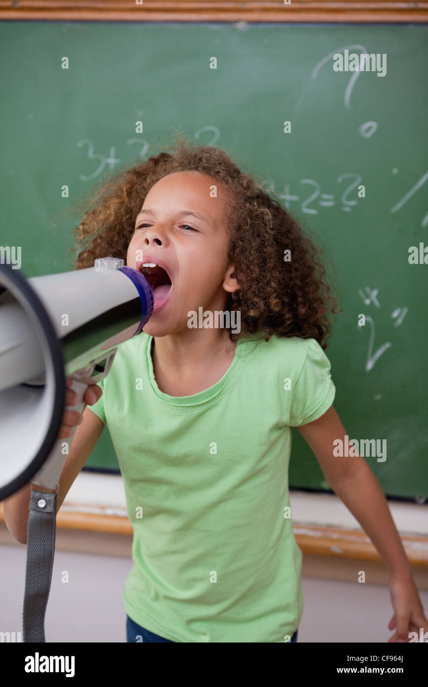 Porträt einer niedlichen Schülerin durch ein Megaphon schreien Stockfoto
