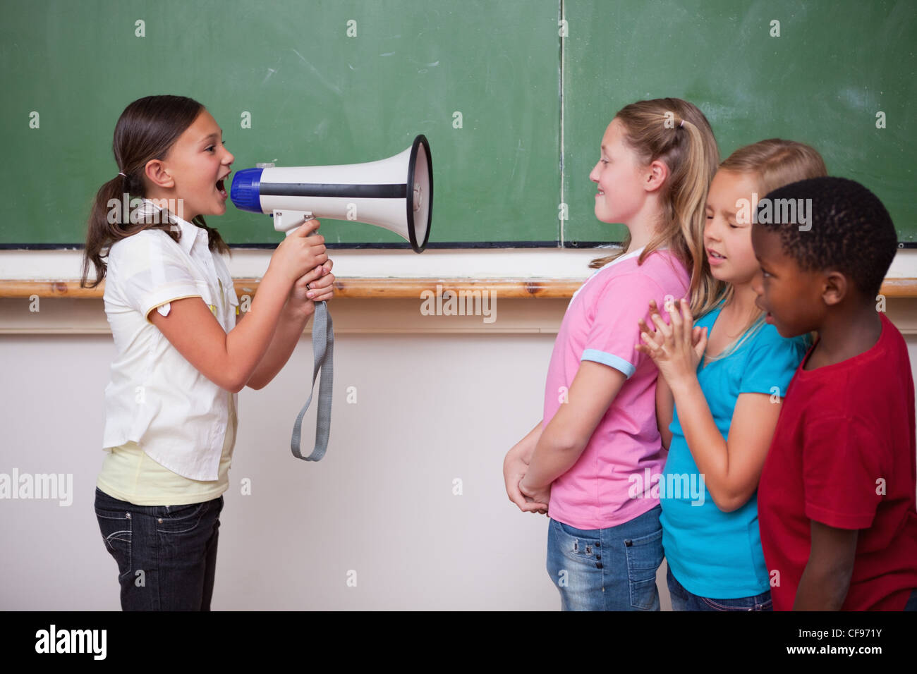 Durch ein Megaphon zu ihren Mitschülern schreien Schulmädchen Stockfoto