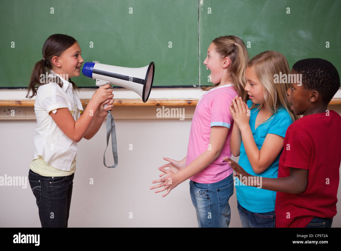 Durch ein Megaphon zu ihren Mitschülern schreien Schulmädchen Stockfoto