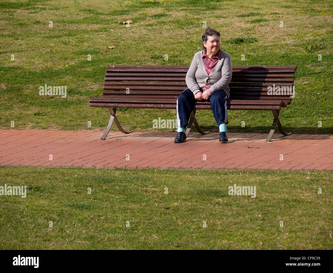 Einsame alte Frau sitzt auf einer Parkbank Stockfoto