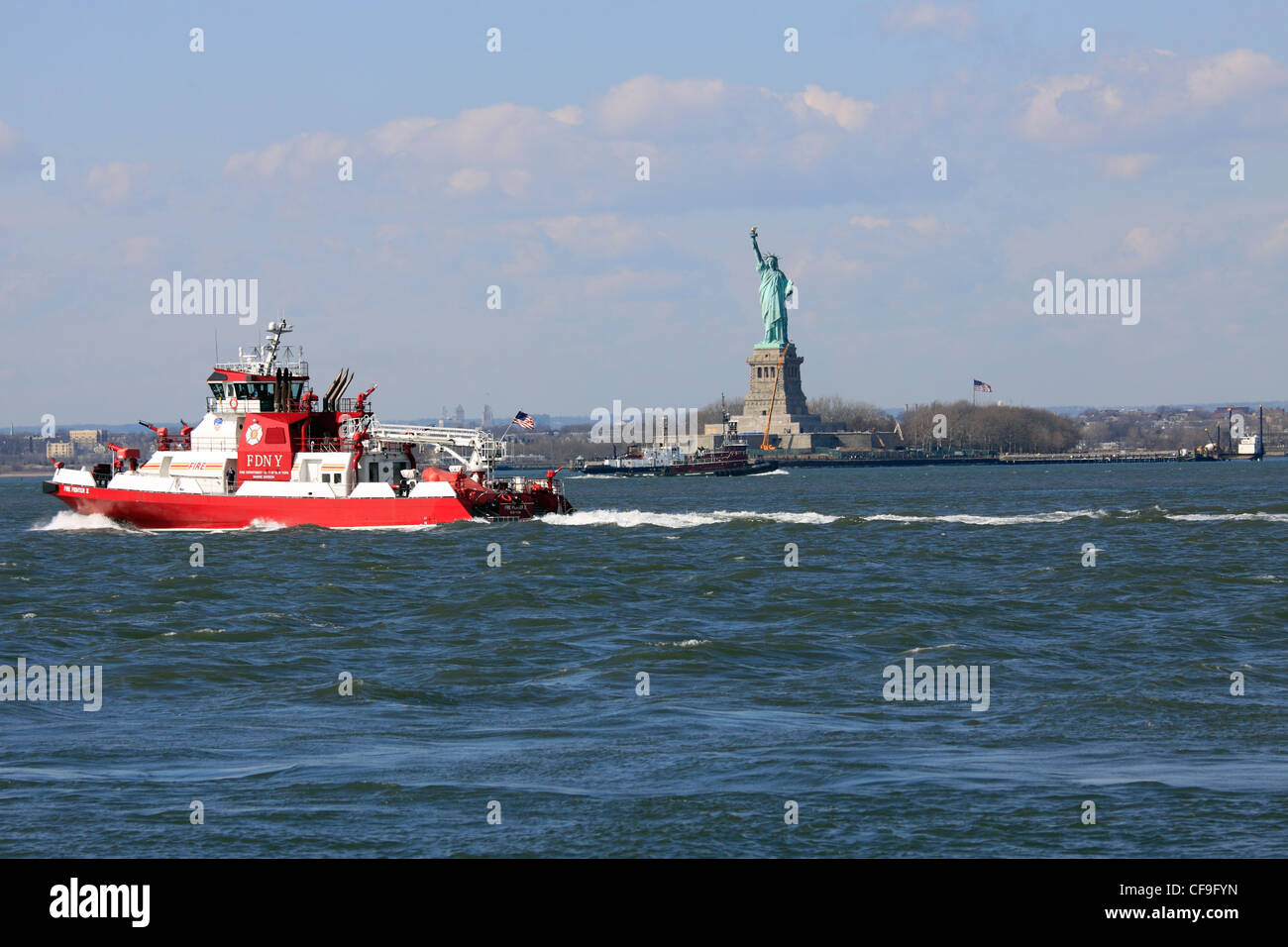 New York City Fire Department Boot vorbei an der Freiheitsstatue im New Yorker Hafen von Red Hook Brooklyn Stockfoto