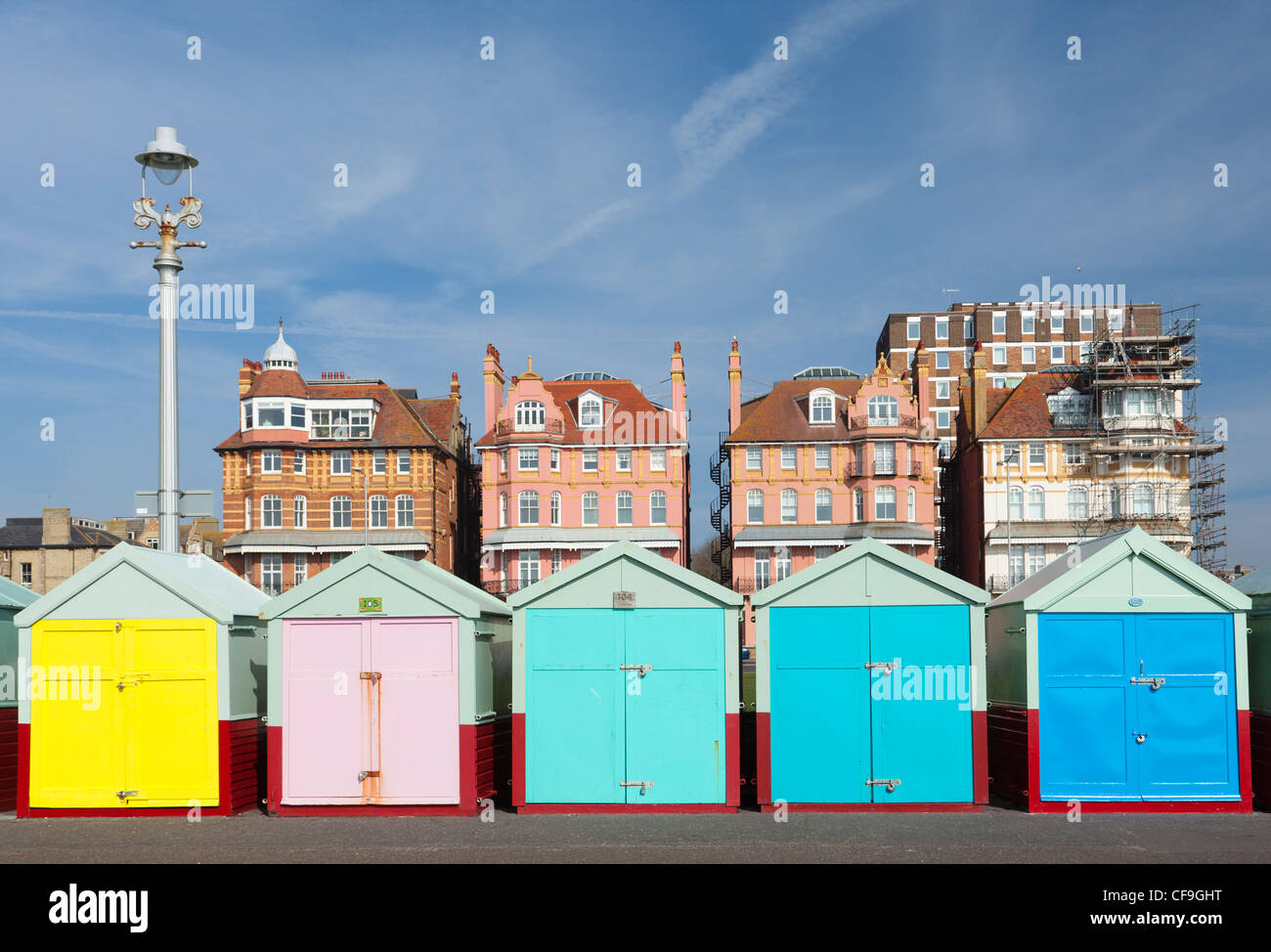 Strandhütten auf Brighton & Hove direkt am Meer mit historischen Gebäuden hinter in leuchtenden Farben Stockfoto