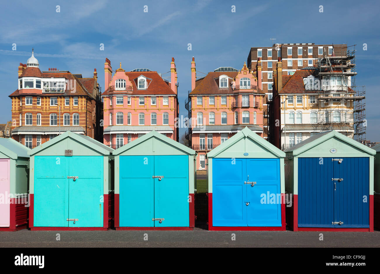 Strandhütten auf Brighton & Hove direkt am Meer mit historischen Gebäuden hinter in leuchtenden Farben Stockfoto