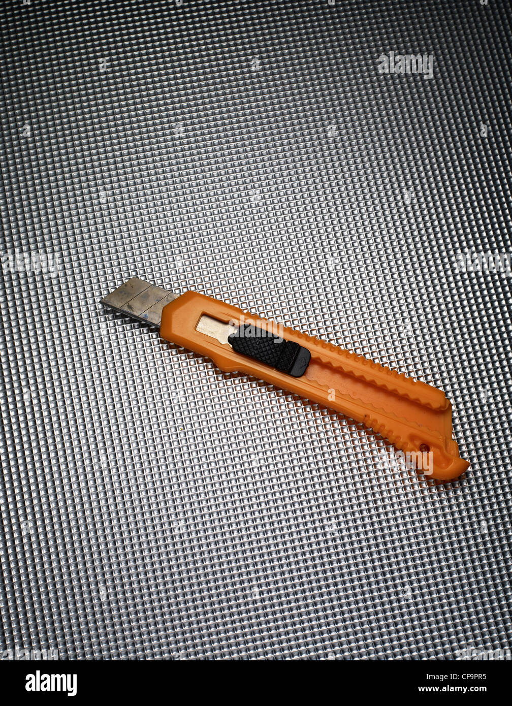eine orange Stanley-Messer auf einem metallischen Hintergrund Stockfoto