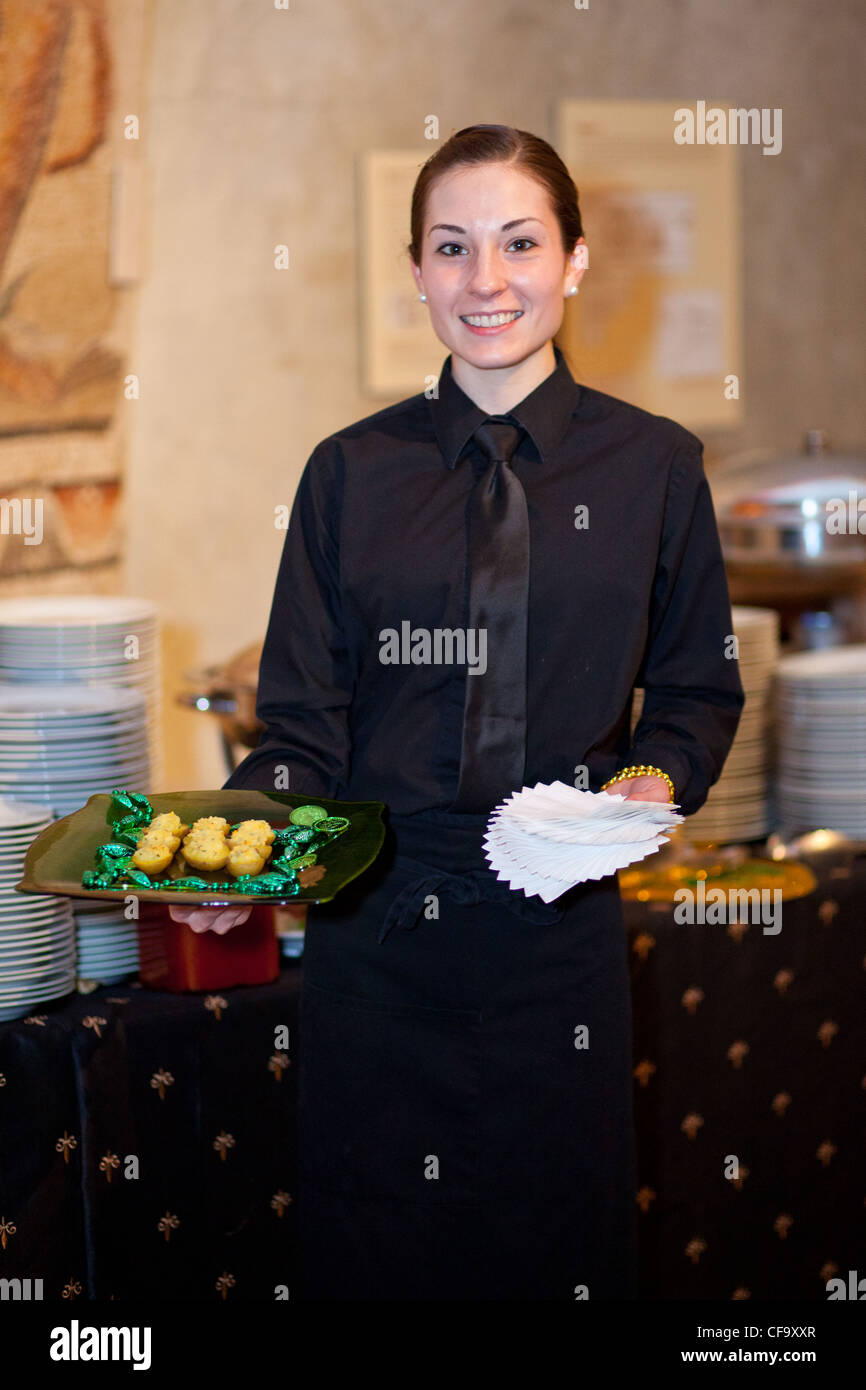 Eine Kellnerin serviert Essen auf einer party Stockfoto
