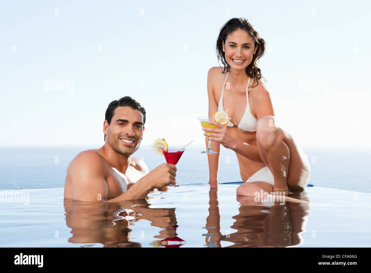 Fröhliches paar mit Cocktails in den pool Stockfoto