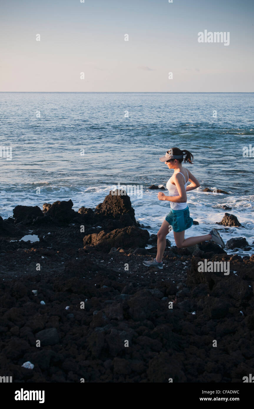 Frau läuft auf felsigen Strand Stockfoto