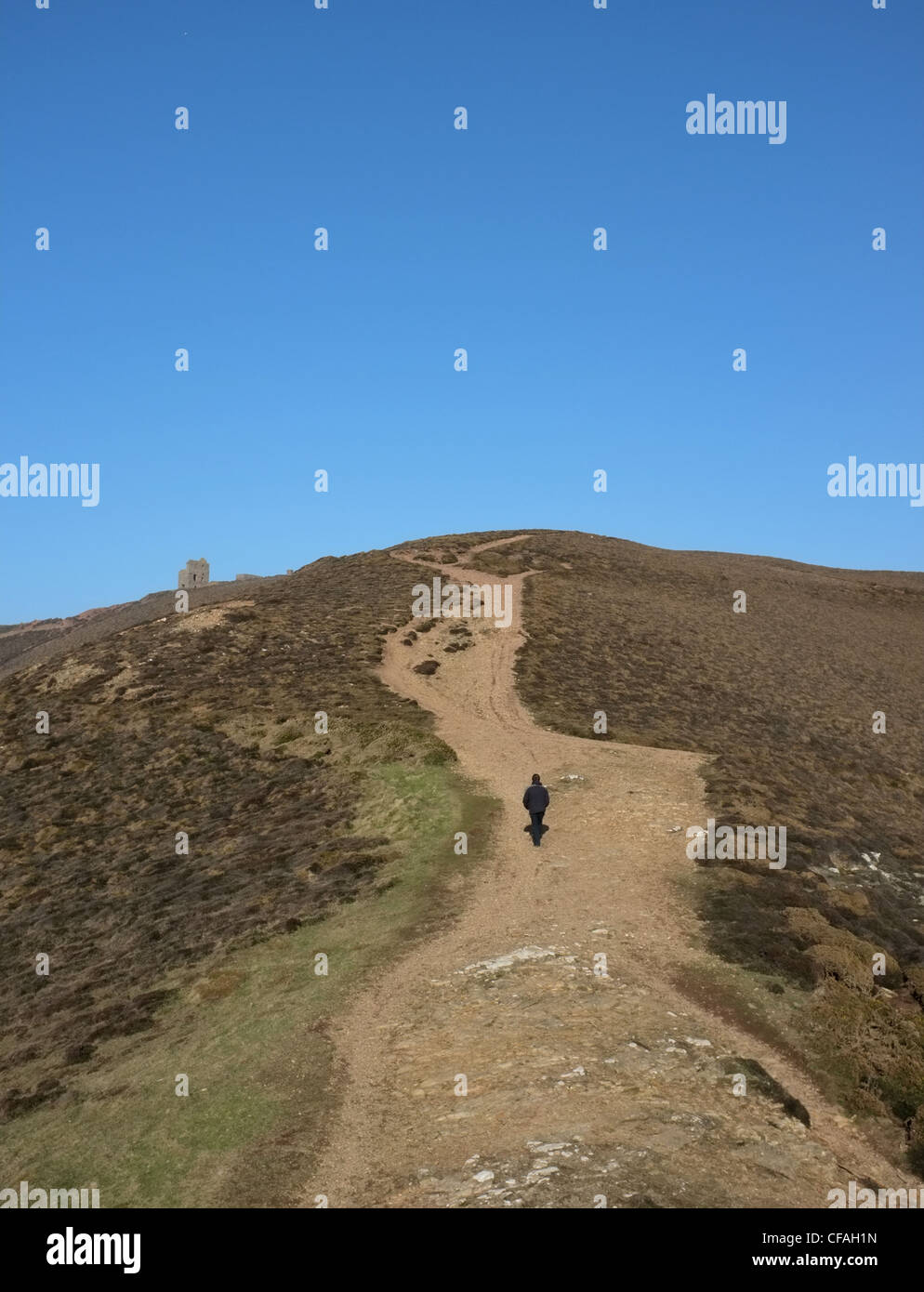 Ein Wanderer auf den Hügeln in der Nähe von St. Agnes in Cornwall im Winter zeigt Wheal Cotes einer Klippe mine Gebäude Stockfoto